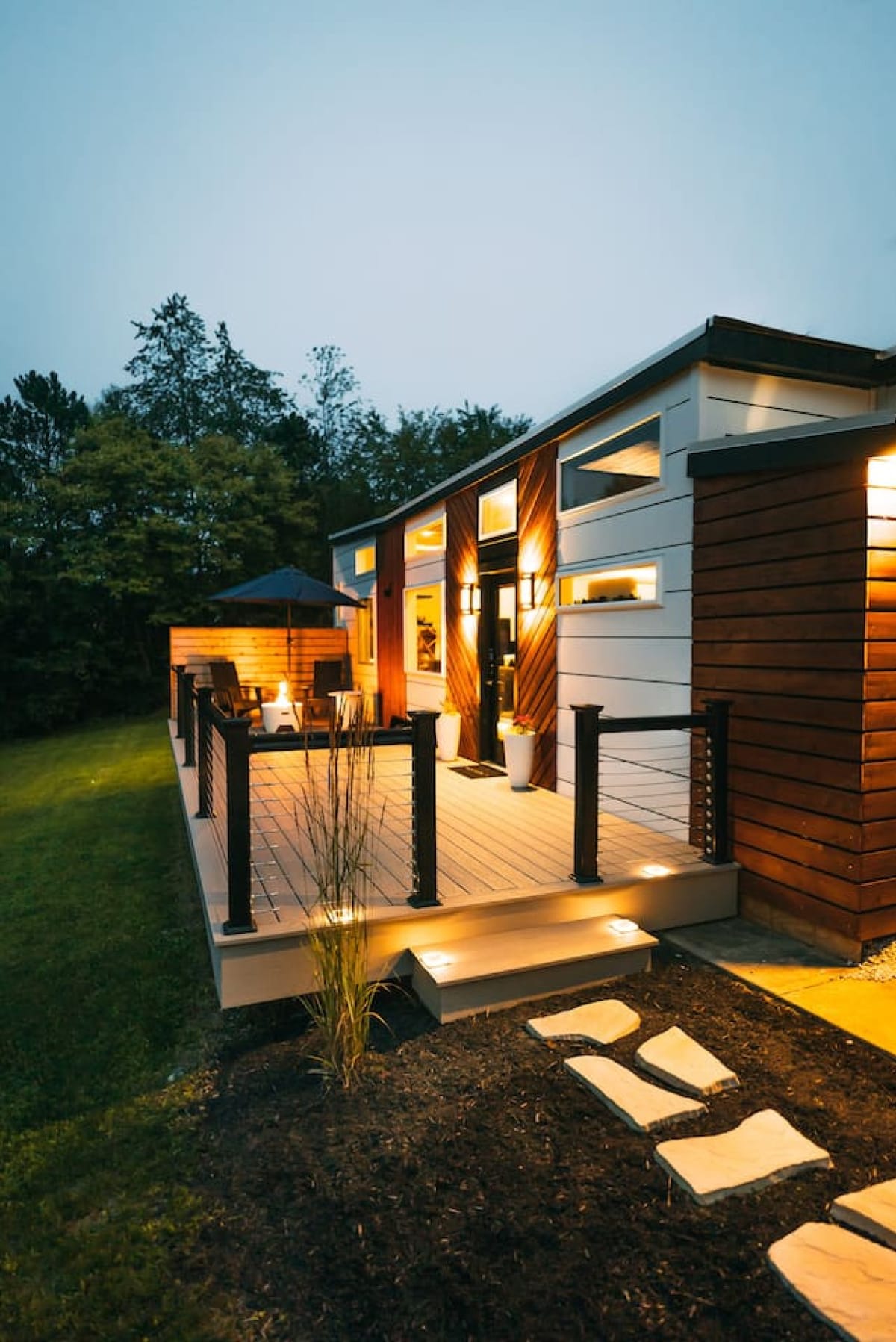 The Lux tiny home at dusk with a butterfly roof, cedar accents, and a lit deck near Berlin, Ohio