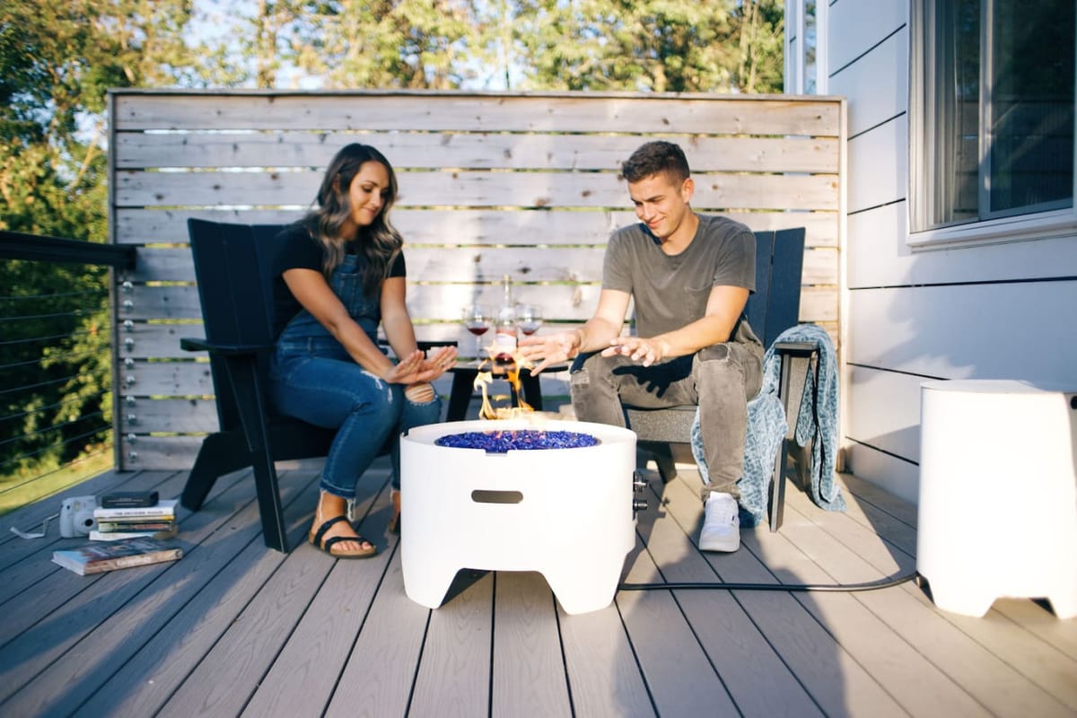 A couple by the fire table on the deck of The Lux tiny home at the end of a date night