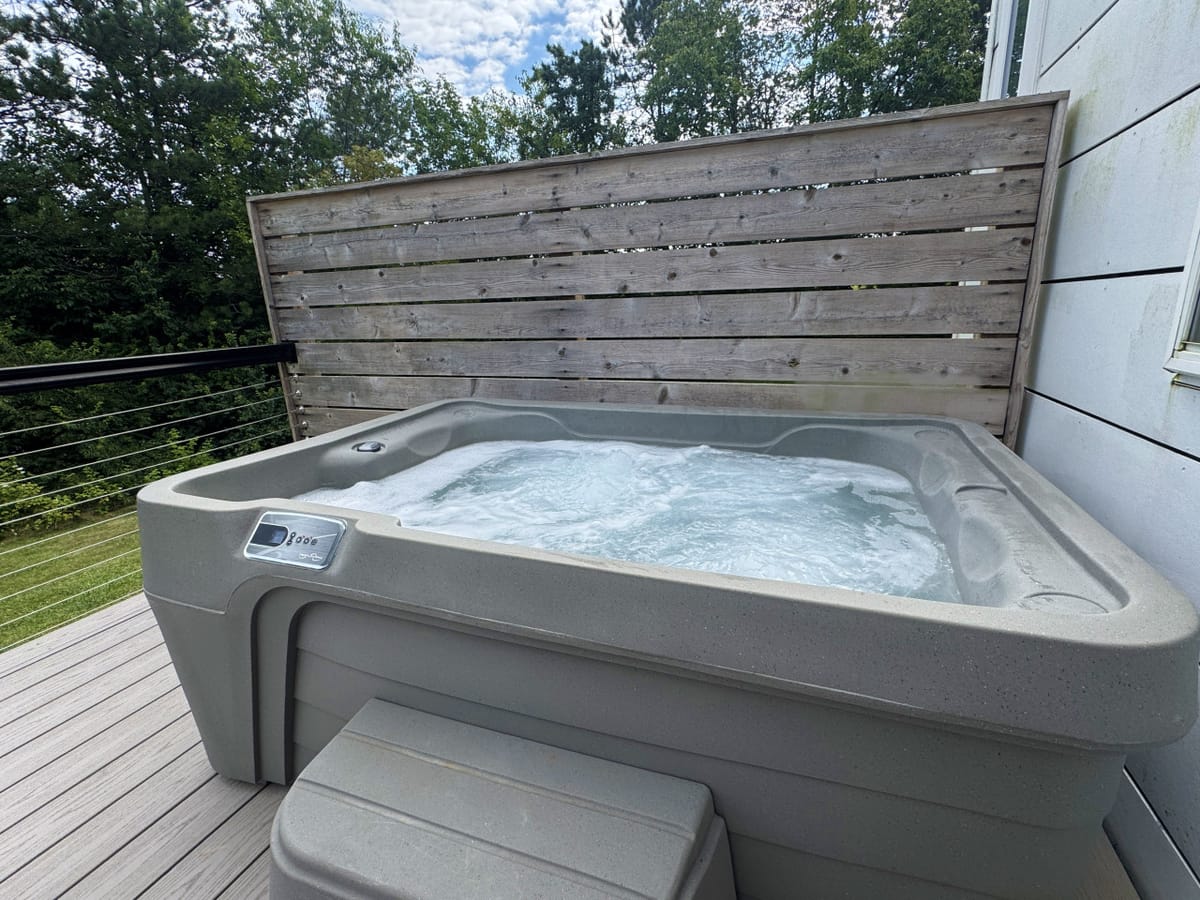 The private outdoor hot tub behind a cedar privacy screen on the deck of The Lux
