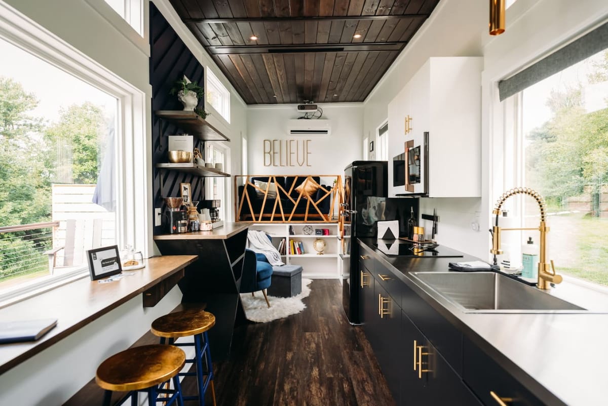 Looking down the length of The Lux: kitchen, coffee bar, and living area under a wood ceiling