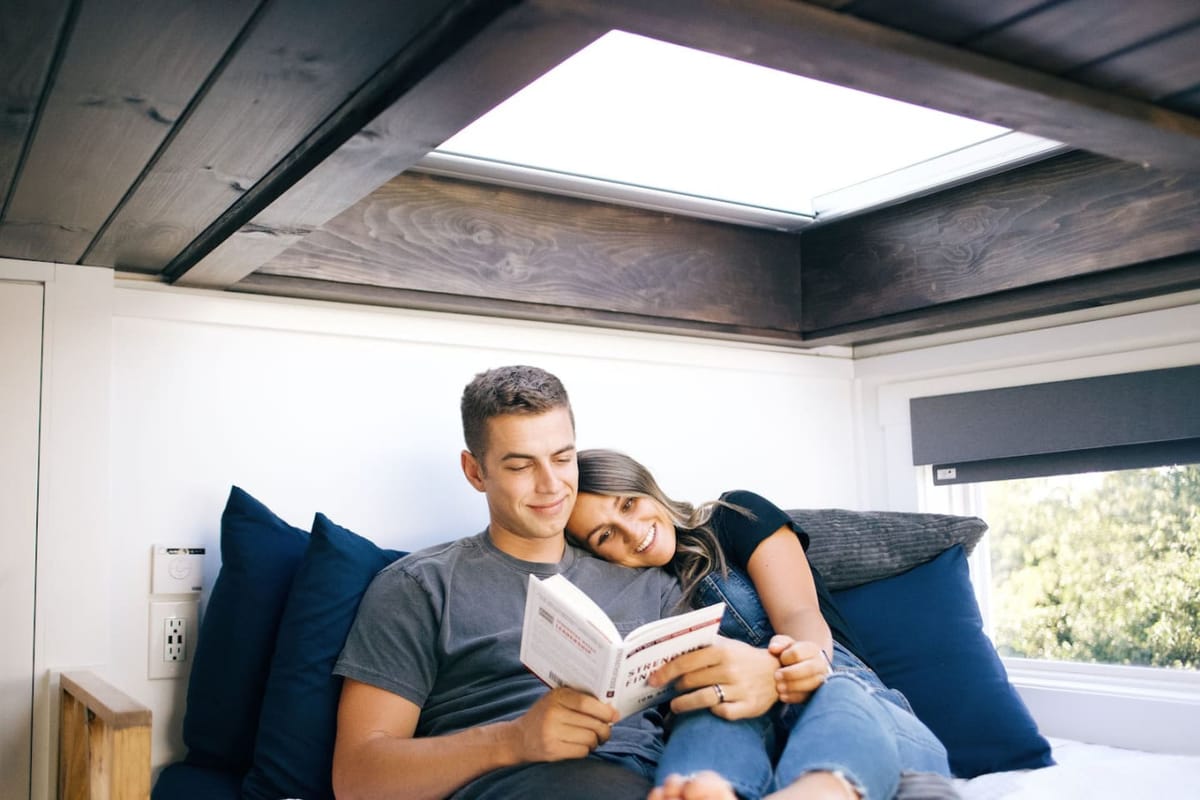 A couple reading together under the skylight in The Lux tiny home