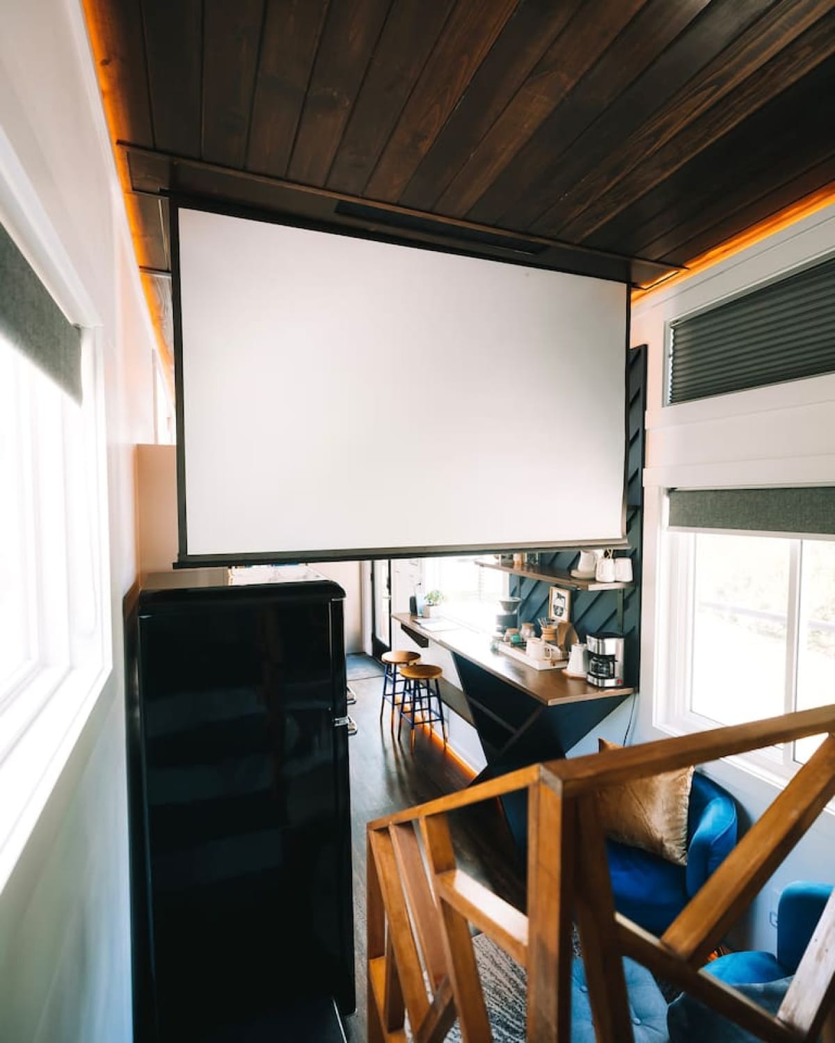 The 90-inch drop-down projector screen in the living area of The Lux tiny home