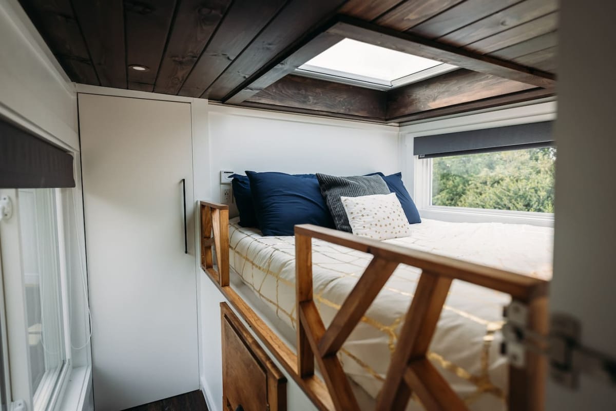 Queen bed beneath an opening skylight in The Lux