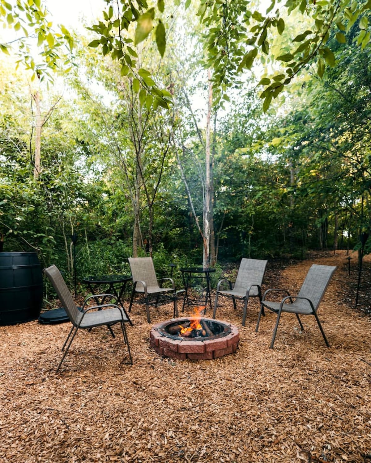The private wood-burning fire pit with four chairs in the woods at The Scandi