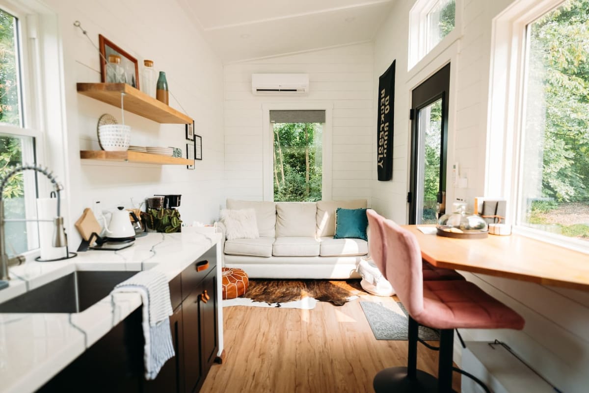 Bright white interior of The Scandi with a sofa, kitchenette, and tall windows