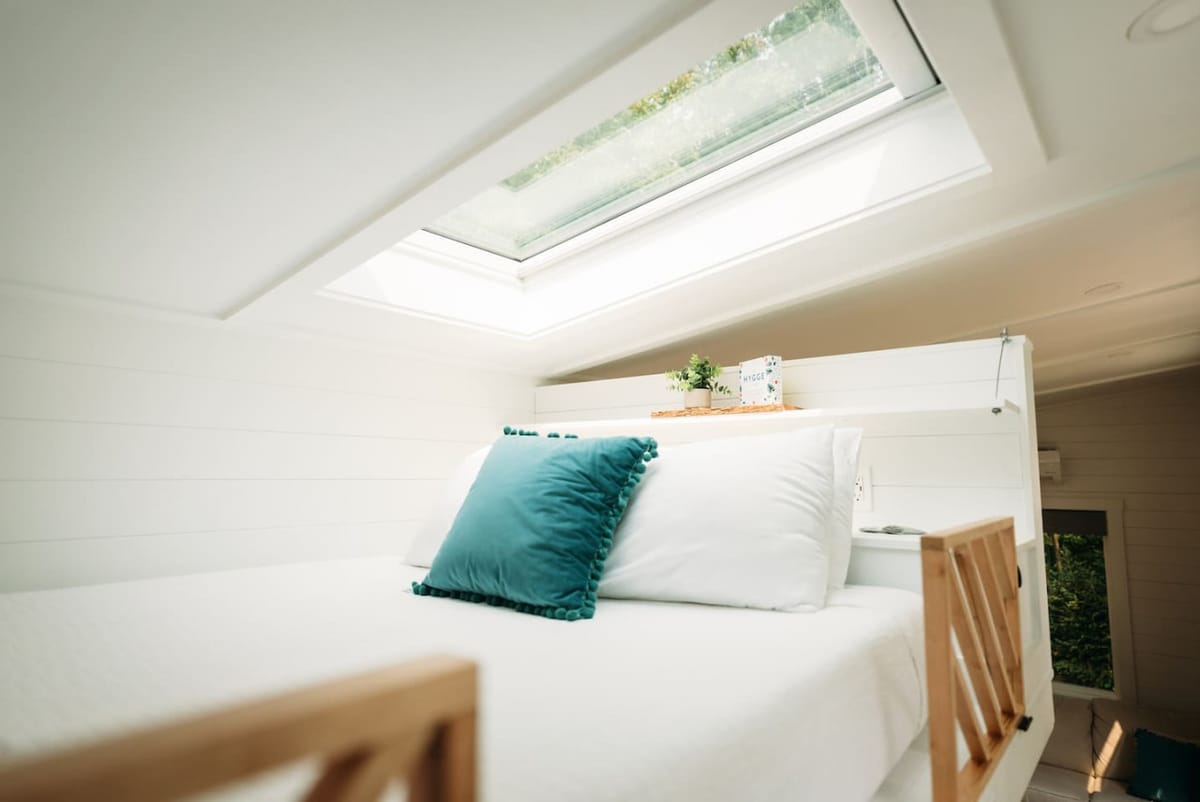Queen bed under an opening skylight in The Scandi tiny home